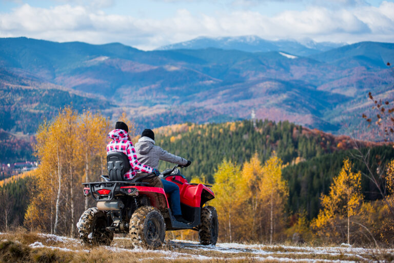 Happy couple on red four-wheeler ATV in mountains